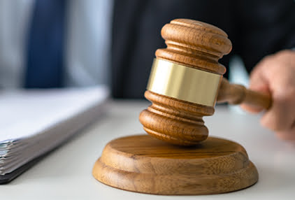 Gavel leaning on its wooden plate.